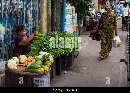 Una donna vendita di verdure fresche dal suo stallo street nel centro di Yangon. Foto Stock