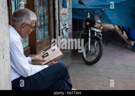 Un cliente legge un libro al di fuori di AA Hussain & Co bookstore che era stato arrestato due anni fa Foto Stock