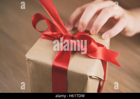 Teen femmina lato andando a sciogliere arco sulla confezione regalo Foto Stock