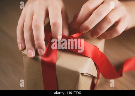 Teen femmina lato andando a sciogliere arco sulla confezione regalo Foto Stock