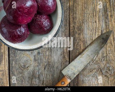 Bollito di barbabietole in smaltò metallo ciotola su una vecchia weathered tavolo in legno Foto Stock