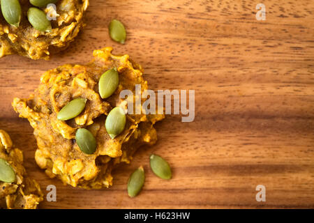 La zucca e caduta di fiocchi d'avena cookie con i semi di zucca in cima, fotografato overhead sul piatto di legno con luce naturale Foto Stock