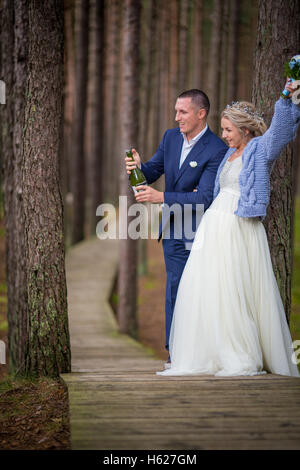 Lo sposo apertura di champagne al giorno di nozze nella foresta Foto Stock