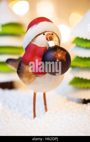 Robin con palla di Natale in una foresta, le luci di Natale in uno sfondo Foto Stock