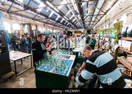 CAMRA beer festival nel vecchio capannone locomotiva a Tunbridge Wells, Regno Unito. La gente la selezione di birre provenienti da vari fusti, barili di birra, a lungo dietro un contatore. Foto Stock