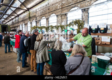 CAMRA beer festival nel vecchio capannone locomotiva a Tunbridge Wells, Regno Unito. La gente la selezione di birre provenienti da vari fusti, barili di birra, a lungo dietro un contatore. Foto Stock