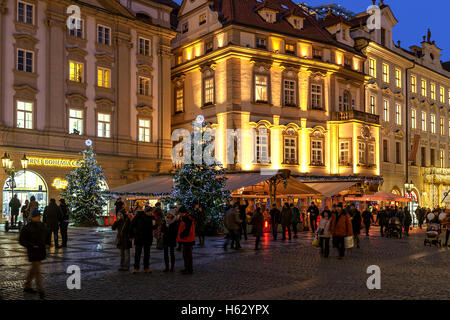 Persone che camminano da edifici illuminati e ristoranti decorati per vacanze di Natale a Praga. Foto Stock