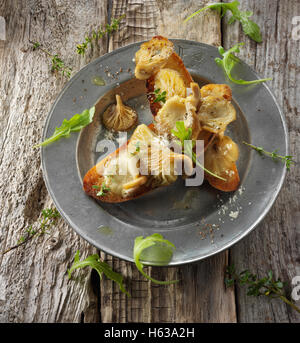 Giallo funghi Oyster saltate in burro e servita sulla pasta acida pane tostato con Wild Rocket Foto Stock