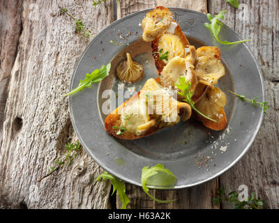Giallo funghi Oyster saltate in burro e servita sulla pasta acida pane tostato con Wild Rocket Foto Stock