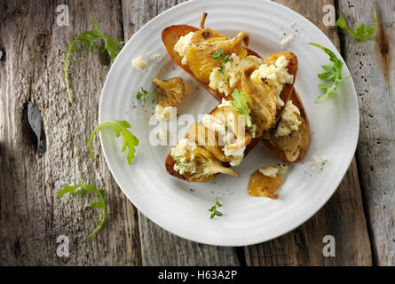 Giallo funghi Oyster saltate in burro e serviti con confuse uovo sulla pasta acida pane tostato con Wild Rocket Foto Stock