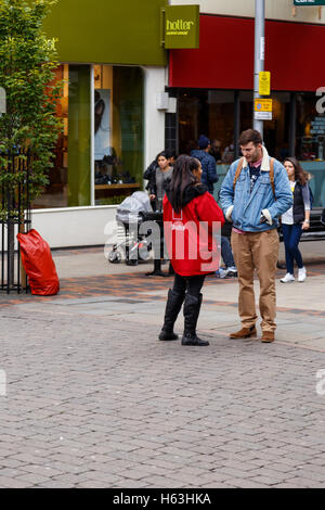 Rifugio femmina street fundraiser parlando di un uomo. In Nottingham, Inghilterra. Foto Stock