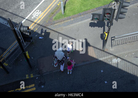 Famiglia immigrata sul marciapiede vicino al semaforo di Glasgow, Scozia Foto Stock