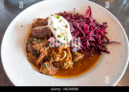 Café pranzo stinco di manzo gulasch speziato al cumino cavolo rosso e panna acida Foto Stock