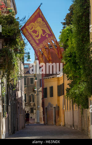 La bandiera di Venezia in una strada tranquilla a Venezia, Italia. La bandiera della regione italiana Veneto. Foto Stock