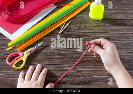 Il bambino creare biglietti di auguri di carta origami miele e Garnett ramo di albero su un tavolo di legno. Fabbricazione di carta origami grena Foto Stock