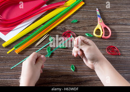 Il bambino creare biglietti di auguri di carta origami miele e Garnett ramo di albero su un tavolo di legno. Realizzazione di strisce di carta melograno Foto Stock