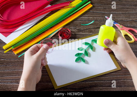 Il bambino creare biglietti di auguri di carta origami miele e Garnett ramo di albero su un tavolo di legno. Realizzazione di strisce di carta melograno Foto Stock