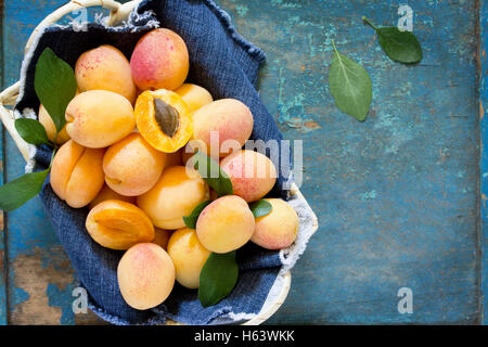 Harvest fresche e mature le pesche in un cesto di vimini sul vecchio tavolo in legno, vista dall'alto. Foto Stock