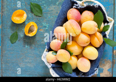 Harvest fresche e mature le pesche in un cesto di vimini sul vecchio tavolo in legno, vista dall'alto. Foto Stock