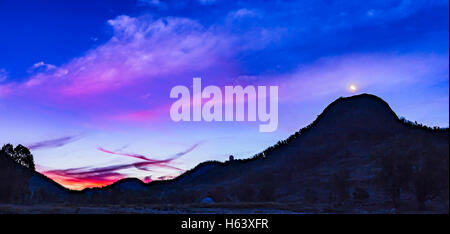 La ceretta a due vecchi di un giorno la luna nel cielo di sera da Australia, alla destra della silhouette della cupola dell'Osservatorio AAT Foto Stock