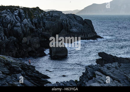 Uno dei pescatori con le loro aste on the rocks, il fondo del mare, costiera nel nord della Cantabria, SPAGNA Foto Stock