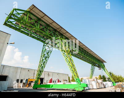 Green gantry crane al lavoro in un magazzino di blocchi di marmo Foto Stock