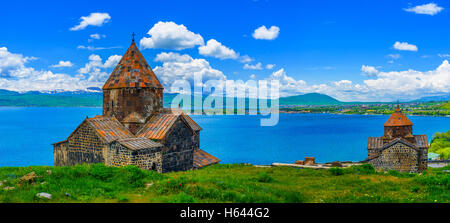 Vista panoramica della penisola di Sevan con entrambe le Chiese del Monastero Sevanavank - Santi Apostoli e la Santa Madre di Dio, sul prato Foto Stock