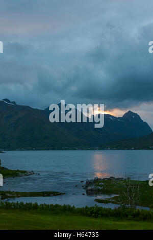 Le montagne circondano questo piccolo villaggio di Sildpollnes, Austvagoy, Lofoten Islands, Norvegia. Sole di mezzanotte in primavera. Foto Stock