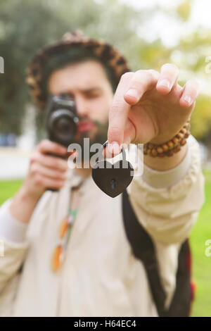 Uomo di cuore di registrazione a forma di serratura di amore nella sua mano con vintage telecamera video Foto Stock