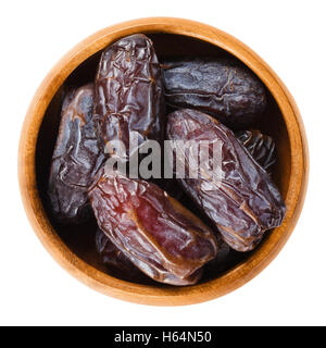 Essiccato Medjool date dal Marocco in una ciotola di legno su sfondo bianco, chiamato anche Mejhool. Grande, dolce e succulenti frutti. Foto Stock