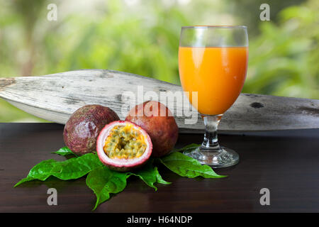 Il frutto della passione fresco e succo di frutto della passione sulla tavola di legno Foto Stock