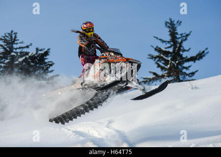 Atleta su una motoslitta spostando in montagna Foto Stock