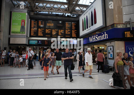 Passeggeri rush nella stazione ferroviaria di Waterloo dove il treno orari sono visibili sul bordo superiore. Londra. 12.08.2016. Foto Stock