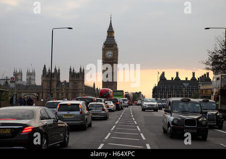 Traffico, double decker bus, taxi e le automobili viaggiano oltre il Westminster Bridge al tramonto con il Big Ben e il Parlamento europeo vede. Foto Stock