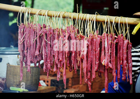 Popolo Lao cottura arrosto di maiale e interiora di maiale alla griglia per la vendita su una vecchia stufa a mercato locale in Laos Foto Stock