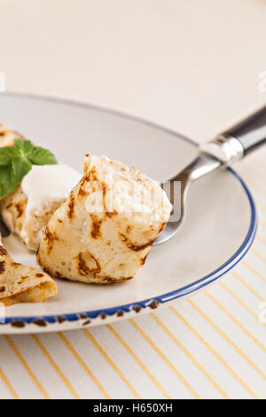 Sottile laminato crepes pancake con panna acida menta su una piastra con coltello e forchetta Foto Stock