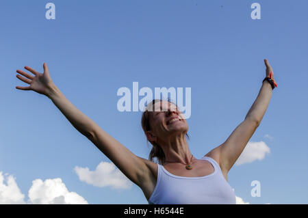 Una giovane donna sollevare o allunga le mani verso il cielo Foto Stock