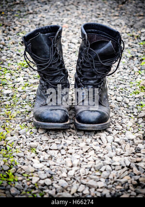 Coppia di un vecchio stivali dell'esercito sulla superficie di pietre Foto Stock