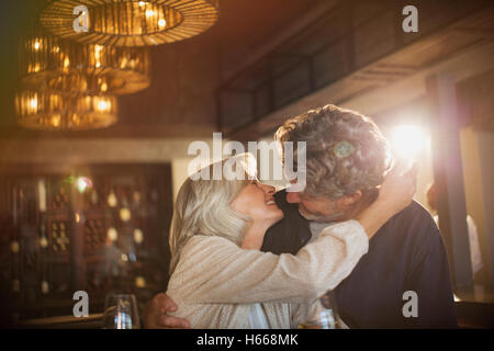 Coppia senior abbracciando e baciando in bar Foto Stock