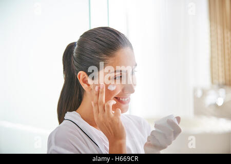 Donna l'applicazione di crema per il viso a guancia Foto Stock