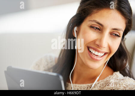 Close up donna sorridente con tavoletta digitale con le cuffie Foto Stock