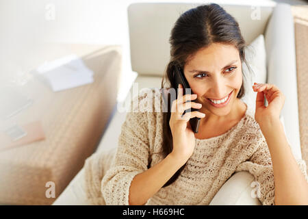 Donna sorridente parlando al cellulare sul divano Foto Stock