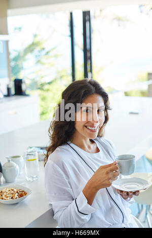Ritratto di donna sorridente in accappatoio di bere il caffè la mattina in cucina Foto Stock