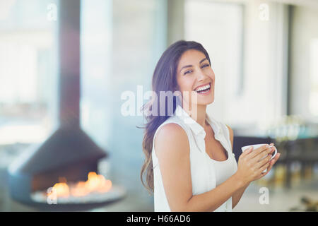 Ritratto di donna sorridente di bere il caffè vicino al camino Foto Stock