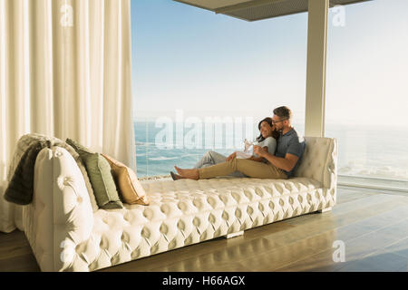 Affettuosa giovane bere vino sulla tufted chaise lounge con vista oceano Foto Stock