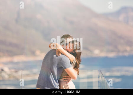 Affettuosa giovane costeggiata sul balcone con vista mare e vista montagna Foto Stock