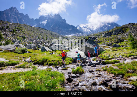 Gli escursionisti che attraversa un flusso sulla Grand Balcon Nord, Valle di Chamonix, sulle Alpi francesi, Francia. Foto Stock