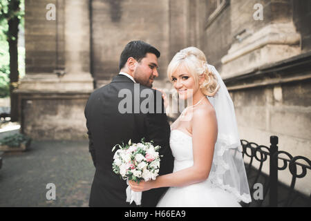 Bel matrimonio felice coppia, sposa con lungo abito bianco in posa nella bella città Foto Stock