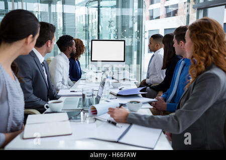 La gente di affari che guarda uno schermo durante una conferenza video Foto Stock