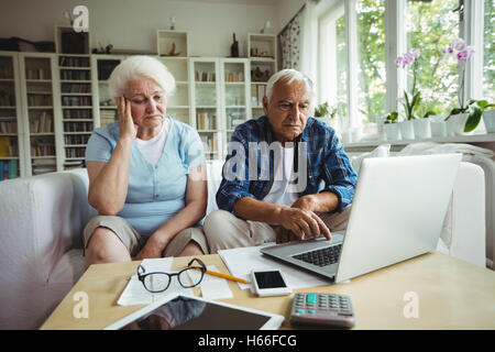 Preoccupato coppia senior utilizzando laptop Foto Stock